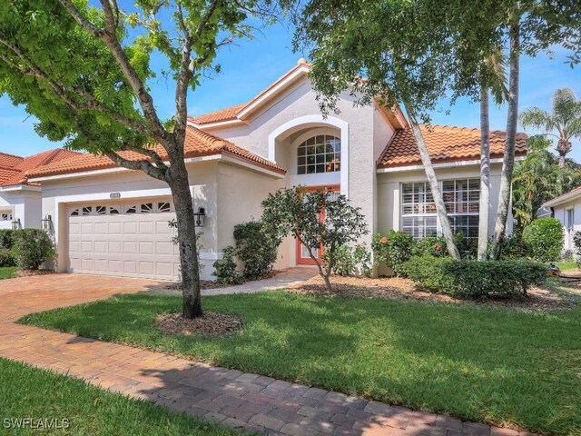 mediterranean / spanish house featuring a garage and a front lawn