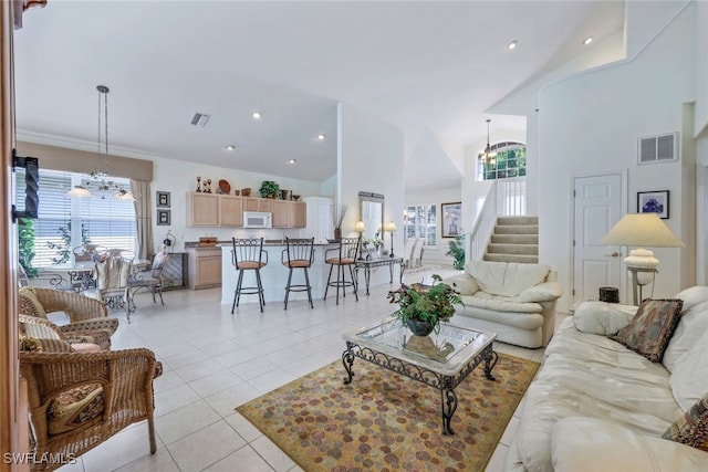 living room featuring light tile patterned floors, a notable chandelier, and high vaulted ceiling