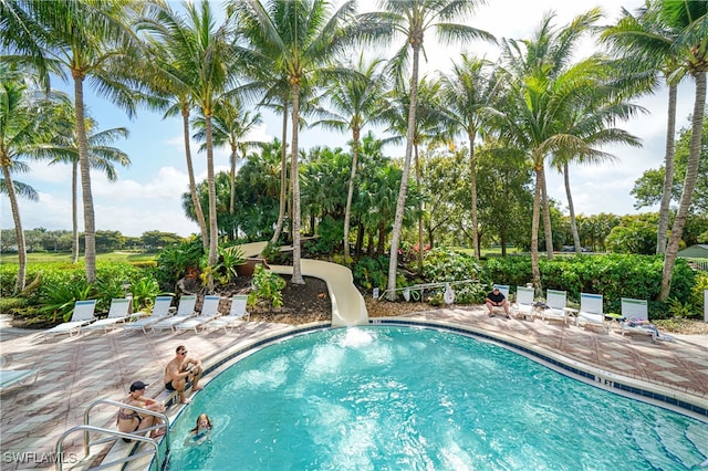 view of swimming pool with a water slide and a patio