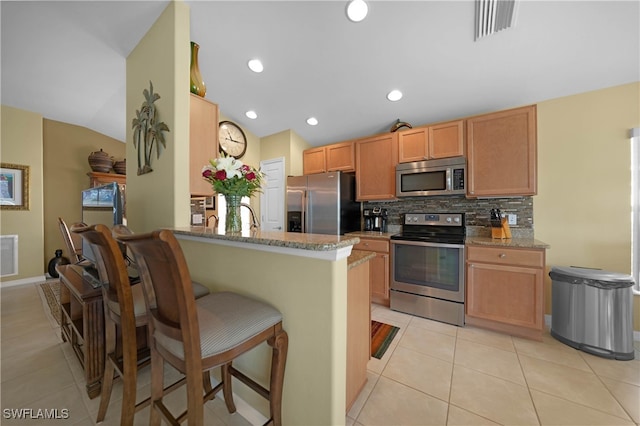 kitchen with stone counters, kitchen peninsula, decorative backsplash, and stainless steel appliances