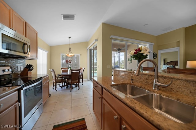 kitchen featuring stainless steel appliances, light tile patterned floors, sink, stone countertops, and decorative light fixtures