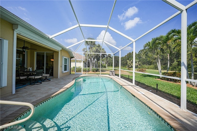 view of pool featuring glass enclosure, a patio, and ceiling fan