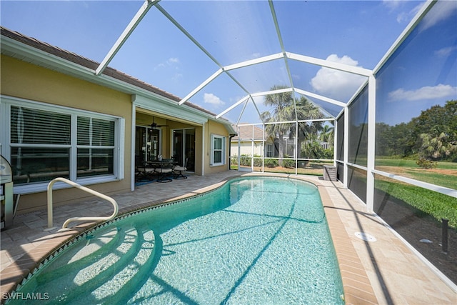 view of pool with ceiling fan, glass enclosure, and a patio area