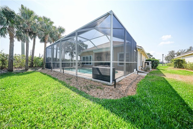 rear view of house featuring glass enclosure and a lawn