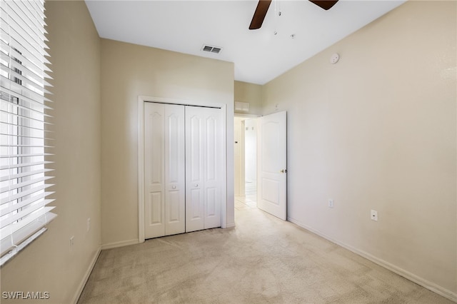 unfurnished bedroom featuring visible vents, a ceiling fan, a closet, baseboards, and light colored carpet