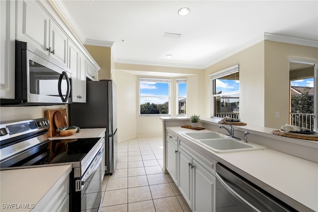 kitchen featuring ornamental molding, a sink, white cabinetry, appliances with stainless steel finishes, and light tile patterned floors