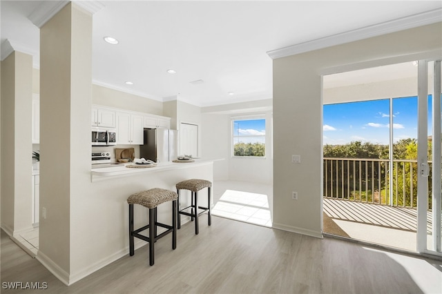 kitchen with a breakfast bar, white cabinets, appliances with stainless steel finishes, light hardwood / wood-style floors, and kitchen peninsula