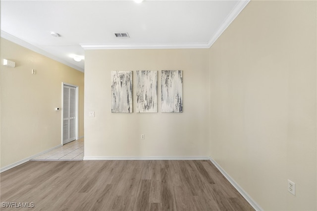 unfurnished room featuring visible vents, wood finished floors, baseboards, and ornamental molding