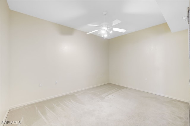 spare room with ceiling fan, baseboards, and light carpet