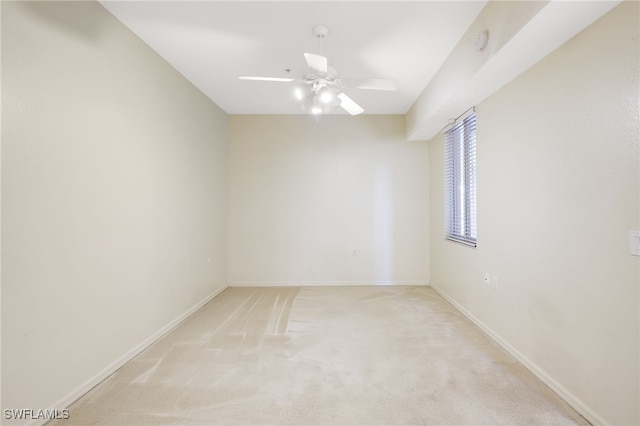 unfurnished room featuring a ceiling fan, light colored carpet, and baseboards