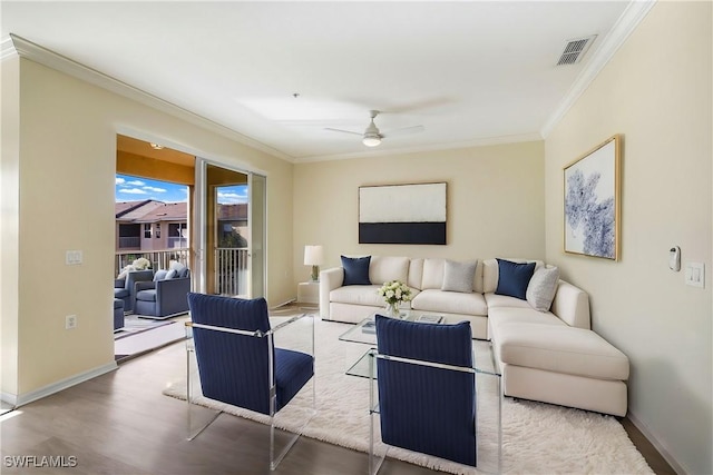 living area featuring visible vents, wood finished floors, baseboards, and ornamental molding