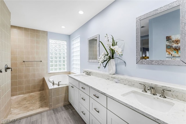 bathroom featuring hardwood / wood-style flooring, vanity, and plus walk in shower