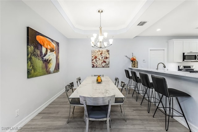 dining space featuring a raised ceiling, crown molding, a chandelier, and dark hardwood / wood-style floors