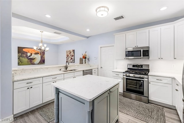 kitchen featuring sink, light wood-type flooring, a notable chandelier, white cabinetry, and stainless steel appliances