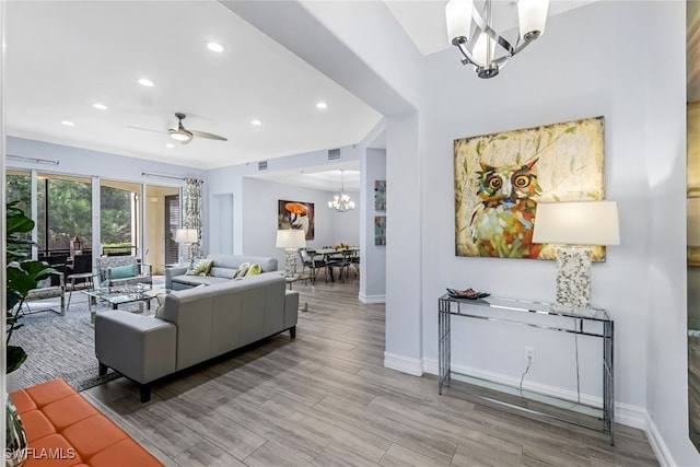 living room with ceiling fan with notable chandelier and light wood-type flooring