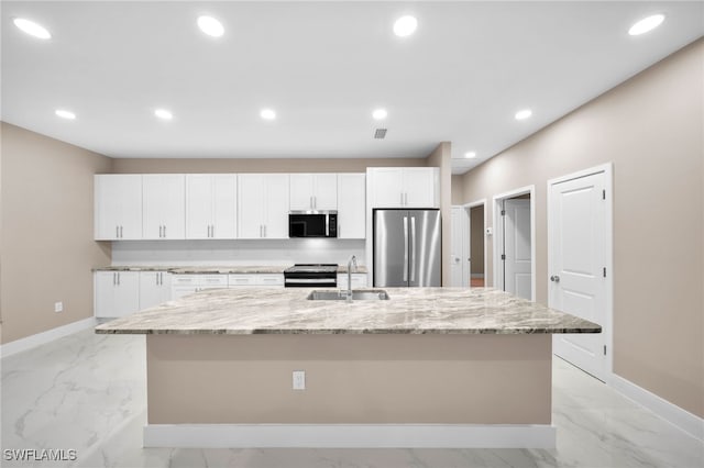 kitchen with light stone counters, sink, a spacious island, appliances with stainless steel finishes, and white cabinetry