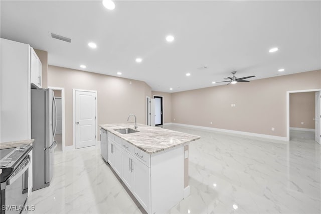 kitchen with light stone countertops, white cabinetry, a kitchen island with sink, and appliances with stainless steel finishes