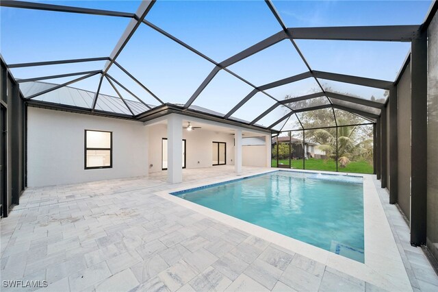 view of pool featuring glass enclosure, a patio, and ceiling fan