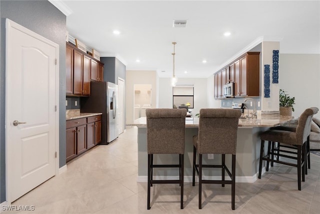 kitchen with kitchen peninsula, hanging light fixtures, a kitchen bar, and crown molding