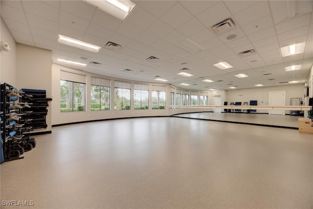 exercise room featuring a paneled ceiling and a wealth of natural light