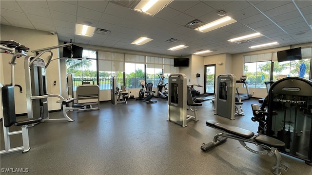 workout area with a drop ceiling and a wealth of natural light