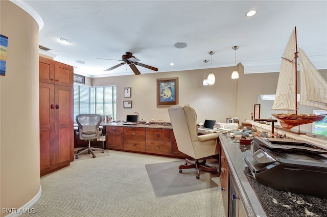 office featuring light carpet, built in desk, ceiling fan, and crown molding