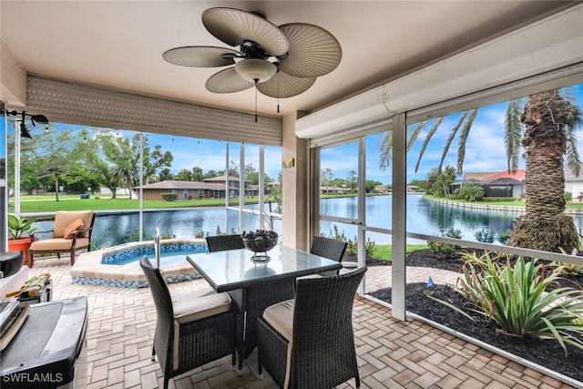 sunroom featuring ceiling fan and a water view