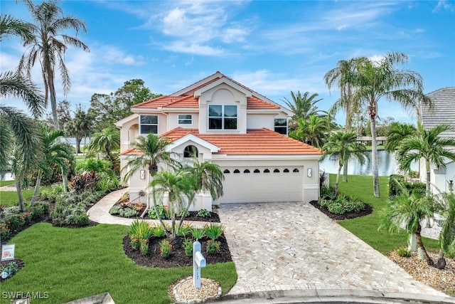 mediterranean / spanish house with a garage, a water view, and a front yard