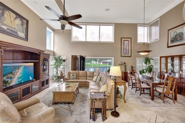 living room featuring ceiling fan, a high ceiling, and ornamental molding