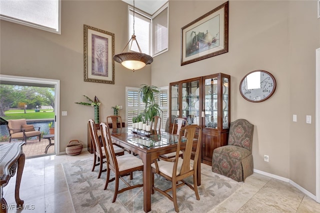 tiled dining space featuring a high ceiling and plenty of natural light