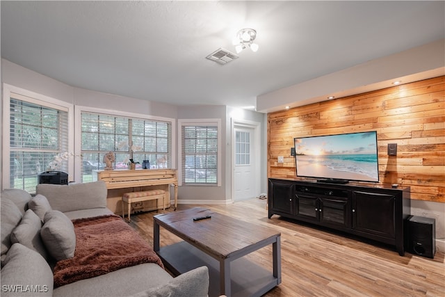 living room with light hardwood / wood-style floors and wooden walls