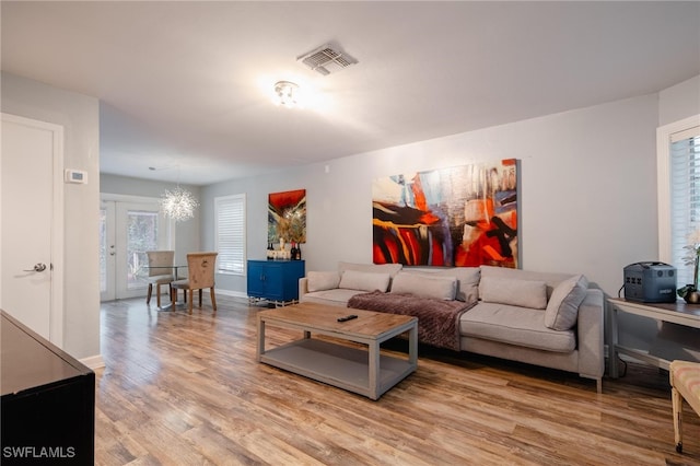 living room featuring a notable chandelier, a healthy amount of sunlight, and light hardwood / wood-style flooring