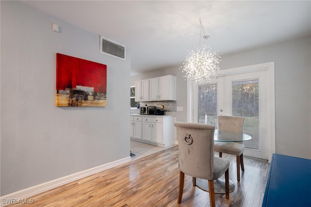 dining space with a chandelier, french doors, and light hardwood / wood-style floors