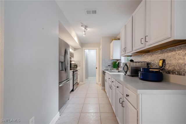 kitchen with tasteful backsplash, light tile patterned flooring, white cabinetry, appliances with stainless steel finishes, and sink