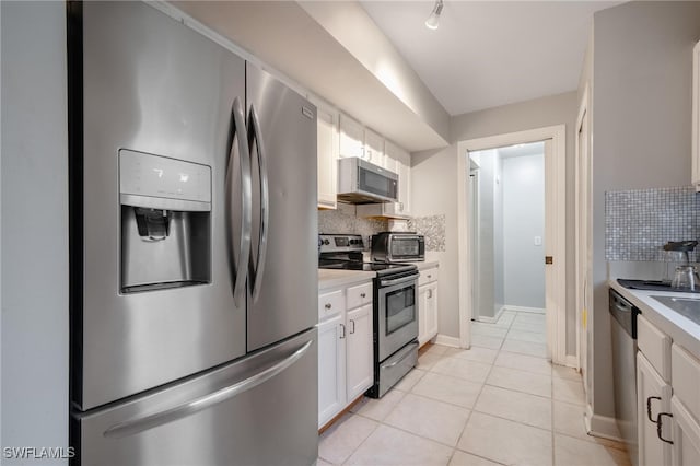 kitchen with tasteful backsplash, white cabinetry, light tile patterned flooring, and stainless steel appliances