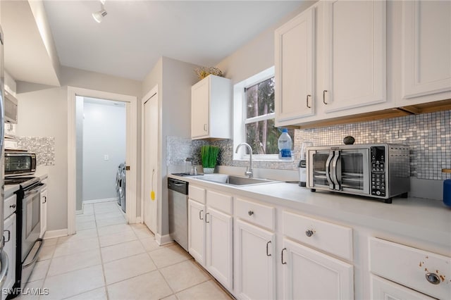 kitchen with stainless steel appliances, light tile patterned floors, decorative backsplash, sink, and white cabinets