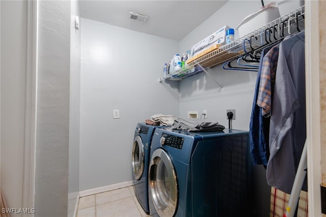 clothes washing area with washing machine and dryer and light tile patterned floors