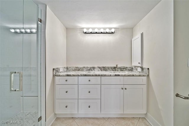 bathroom with tile patterned flooring, vanity, and walk in shower