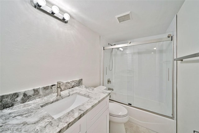 full bathroom featuring shower / bath combination with glass door, tile patterned flooring, vanity, and toilet