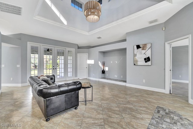 living room featuring a notable chandelier, a tray ceiling, ornamental molding, and french doors