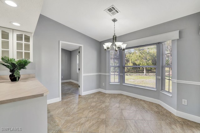 unfurnished dining area featuring an inviting chandelier, light tile patterned flooring, and vaulted ceiling