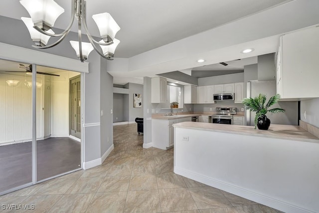 kitchen with appliances with stainless steel finishes, pendant lighting, white cabinets, kitchen peninsula, and an inviting chandelier