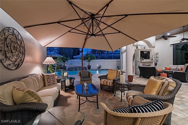 view of patio with an outdoor living space with a fireplace and ceiling fan