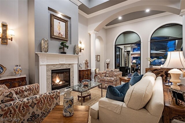 living room featuring ornamental molding, a high end fireplace, and ornate columns