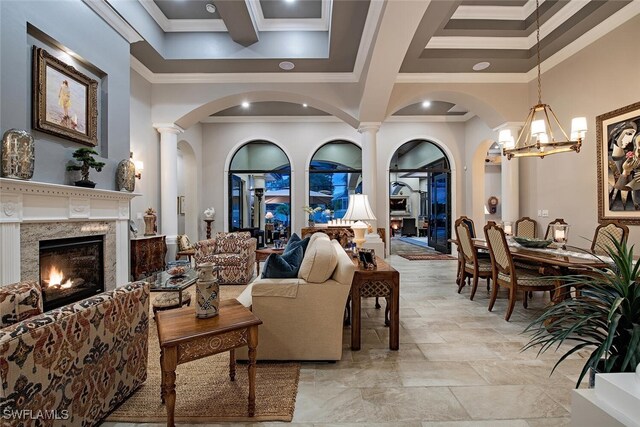 living room with beam ceiling, a high end fireplace, ornamental molding, and a notable chandelier