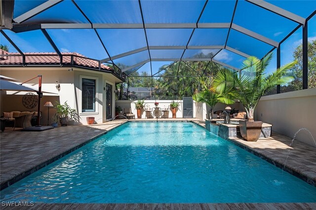 view of pool with a lanai, a patio area, and pool water feature