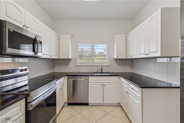 kitchen with tasteful backsplash, stainless steel appliances, sink, light tile patterned floors, and white cabinets