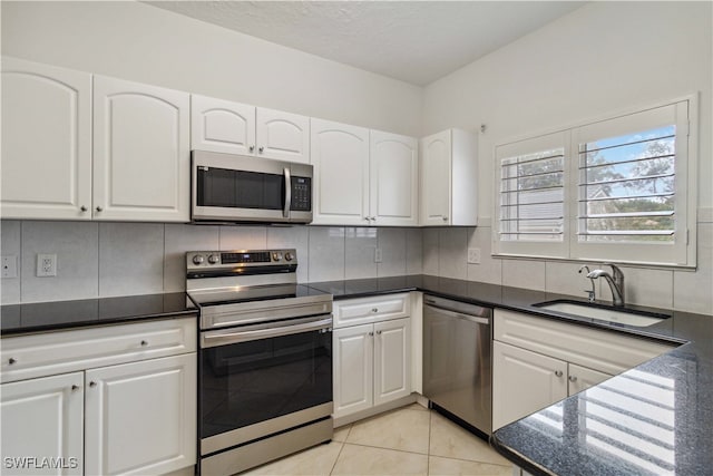 kitchen with appliances with stainless steel finishes, backsplash, white cabinetry, and sink