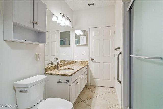 bathroom featuring toilet, a textured ceiling, vanity, and tile patterned floors