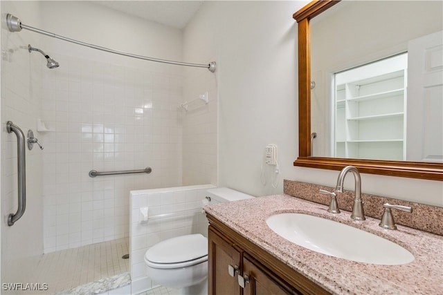 bathroom featuring vanity, toilet, and tiled shower